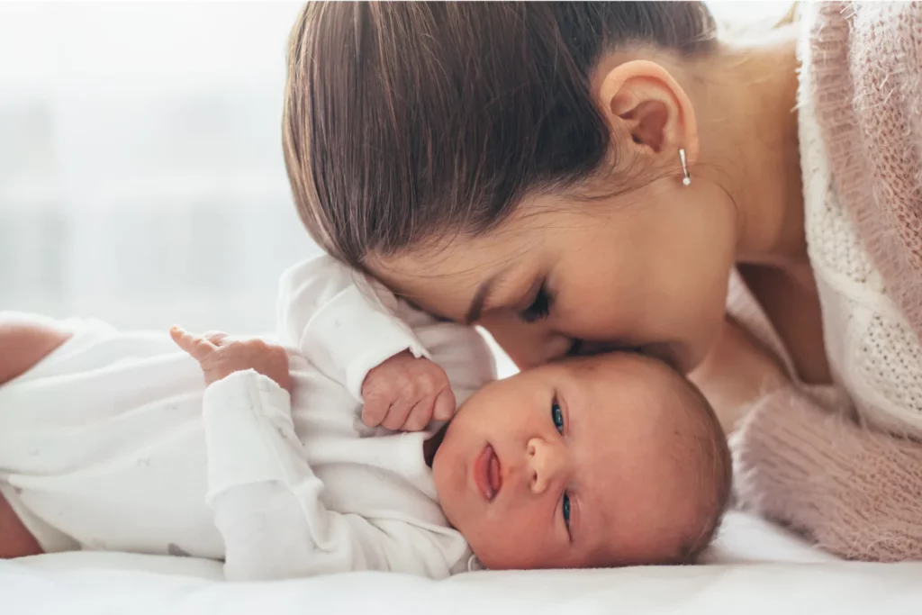 Mutter küsst Neugeborenes zärtlich, warm und generationsübergreifend