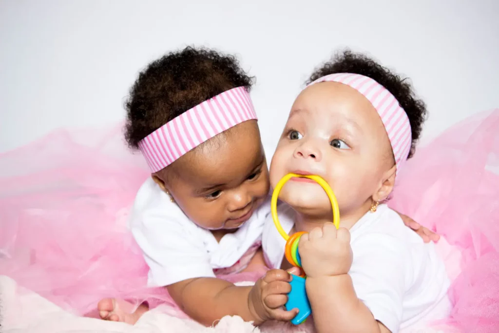 Zwei Babys mit Spielzeug und Haarbändern