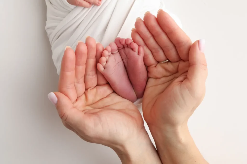 Zwei Hände halten Babyfüße.
