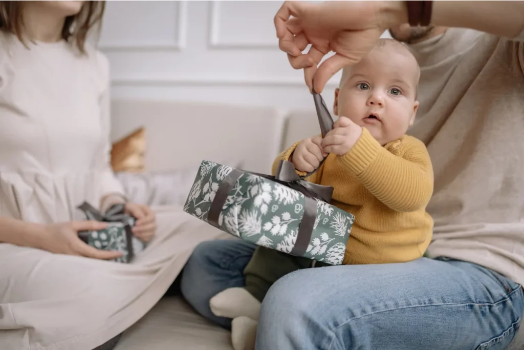 Baby öffnet Geschenk mit Eltern.